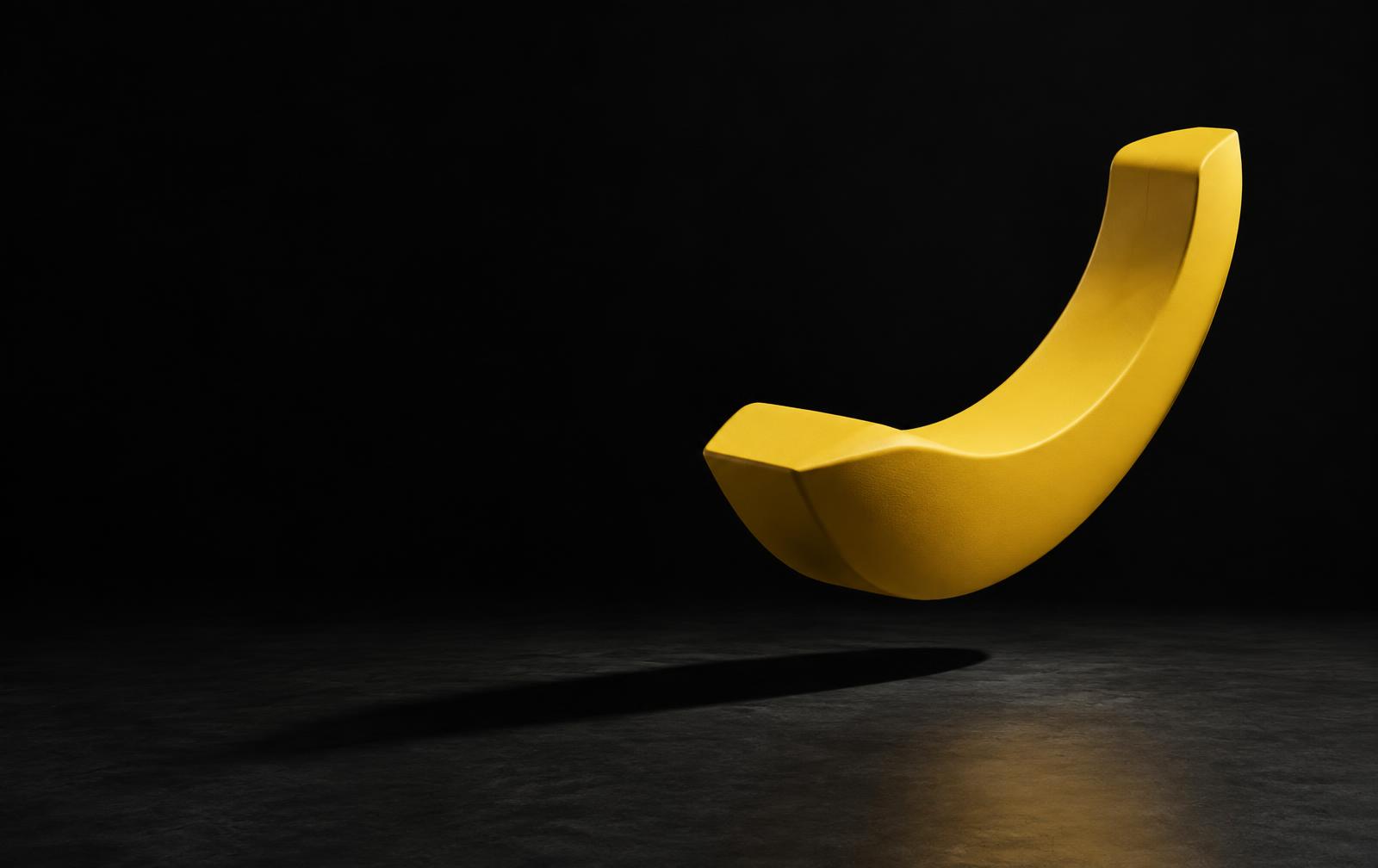 Sculptural banana-yellow symbol in a dark studio